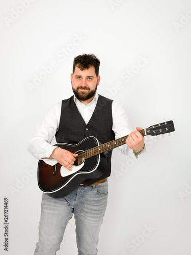 man with black hair and beard playing and singing with acoustic guitar on white background and is happy