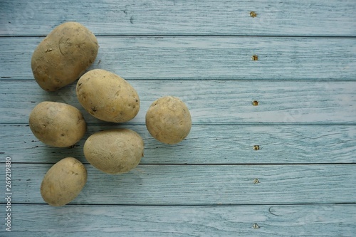 Fresh raw potatoes on wooden blue background, top view