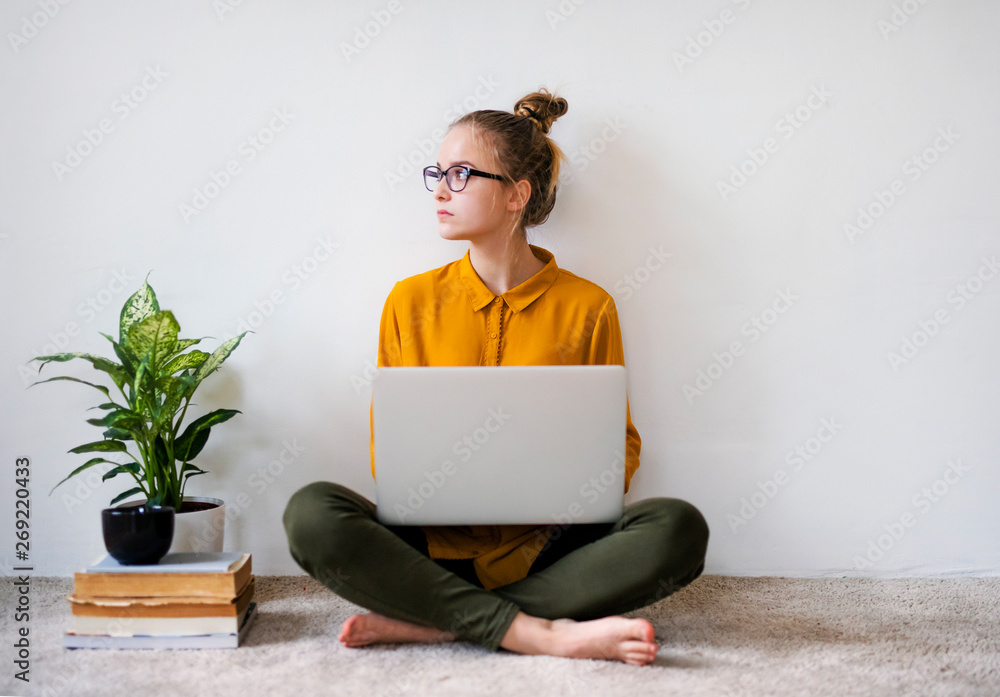 A young female student sitting on floor using laptop when studying.