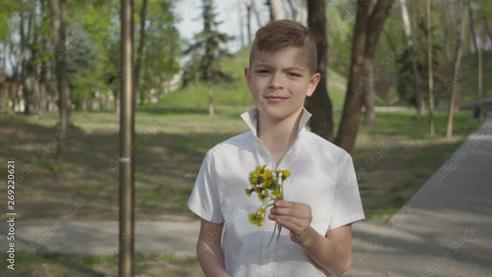 Young boy with dandelion flowers waiting to give a bouquet for person. Outdoor recreation. Young boy with dandelion flowers waiting to give a bouquet for person. Outdoor recreation.