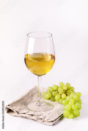 Glass of White Wine and Branch of Green Grapes on White Background