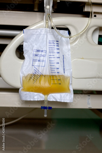 plastic urine collection bag hang under patient bed in hospital 
