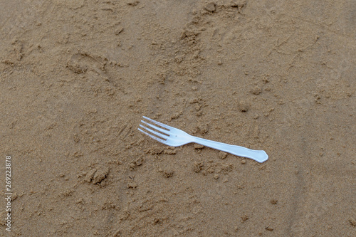 White plastic fork on the beach. Plastic environment pollution concept.