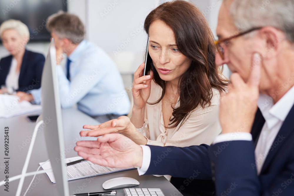 Busy woman analysing the charts and talking by mobile phone Busy woman analysing the charts and talking by mobile phone