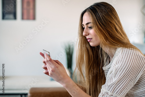 Happy woman with smartphone on couch