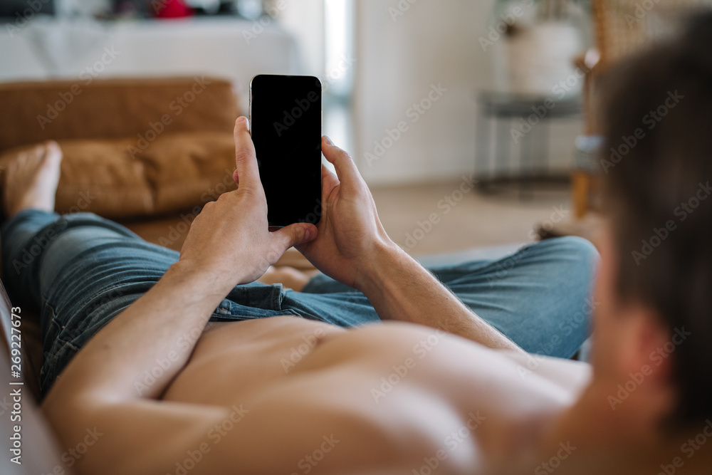 Happy man with smartphone on couch Happy man with smartphone on couch
