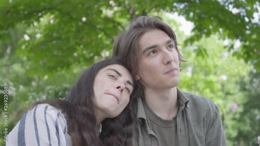 Portrait pretty young couple in love wearing casual clothes sitting at the bench talking and holding hands. Happy girl and boy spending time together in the park. Leisure outdoors Portrait pretty young couple in love wearing casual clothes sitting at the bench talking and holding hands. Happy girl and boy spending time together in the park. Leisure outdoors