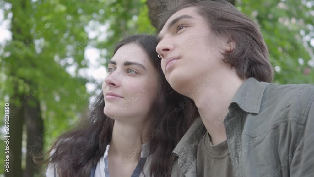 Portrait pretty young couple in love wearing casual clothes sitting at the bench talking and holding hands. Happy girl and boy spending time together in the park. Leisure outdoors Portrait pretty young couple in love wearing casual clothes sitting at the bench talking and holding hands. Happy girl and boy spending time together in the park. Leisure outdoors