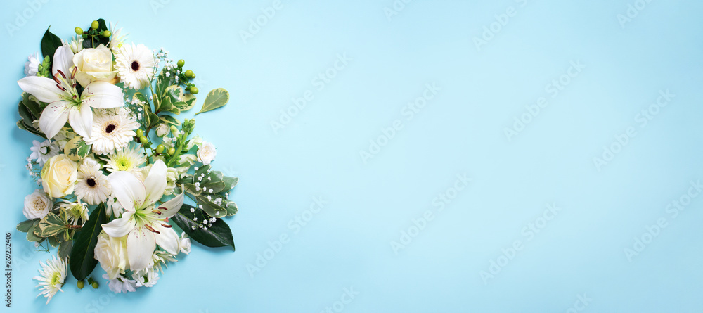 Spring composition of white flowers on blue paper background with copy space. Creative layout. Flat lay. Top view. Summer minimal concept.