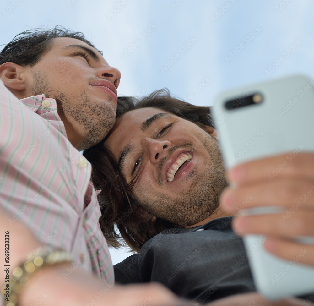 Happy gay couple enjoying with the mobile phone Happy gay couple enjoying with the mobile phone