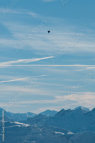 An air balloon set against the mountain tops and clouds in a sunny day