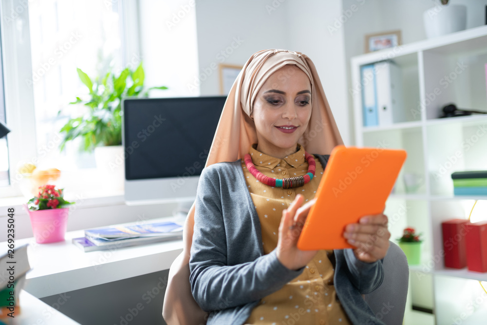 Appealing Muslim woman reading e-book feeling joyful Appealing Muslim woman reading e-book feeling joyful