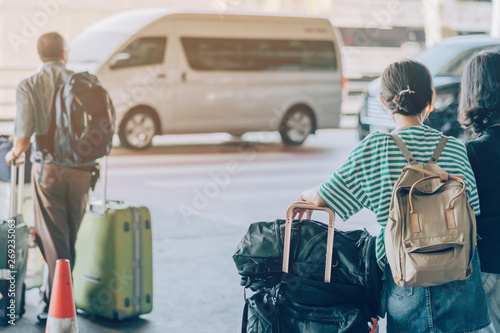 Photos Passengers with big roller luggage stand to wait for the car to pick up at airport arrival terminal