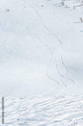 Trails left by skiers and snowboarders in deep snow on the slope