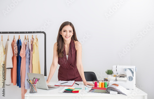 Portrait of beautiful smile asian designer woman with computer in tailer fabric fashion small business workshop. Young owner startup entrepreneur. creative girl textile sme business concept photo