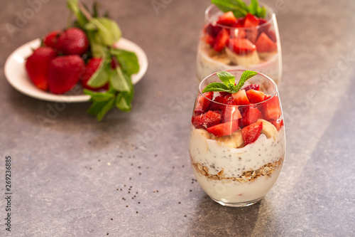 Homemade yogurt parfait with granola, strawberries, bananas and Chia seeds in glasses. Diet dessert with yogurt, Chia, muesli and fresh berries. Healthy breakfast 
