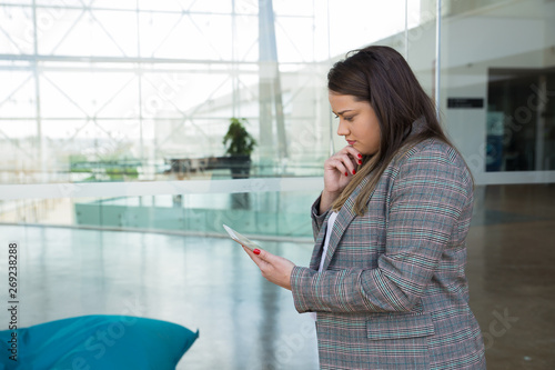 Thoughtful business woman using tablet outdoors. Lady standing and holding gadget with glass wall in background. Business and technology concept. Side view. Free Download Thoughtful business woman using tablet outdoors. Lady standing and holding gadget with glass wall in background. Business and technology concept. Side view. - GFXLoad