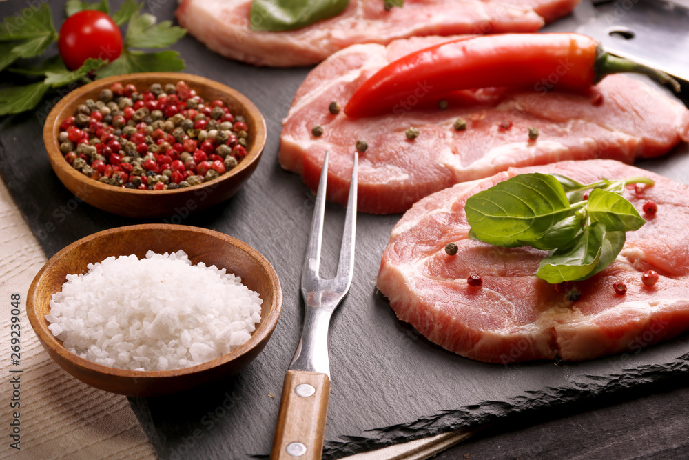 Raw pork meat steak with vegetables, peppers, tomato, salt, rosemary and spices cooking over stone table. Top view. Raw pork meat steak with vegetables, peppers, tomato, salt, rosemary and spices cooking over stone table. Top view.