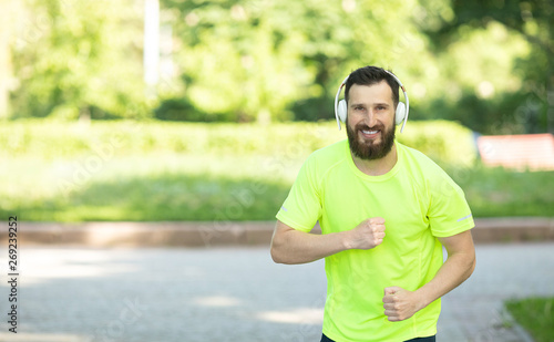 Running man jogging in city street park at beautiful summer day. Sport fitness model caucasian ethnicity training outdoor. 