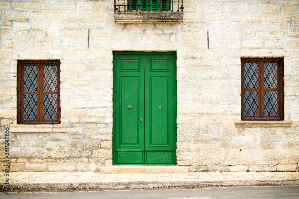 Architecture details from the Renaissance - green painted wooden door and two windows with a grate of a stone house in Kavarna city, Bulgaria