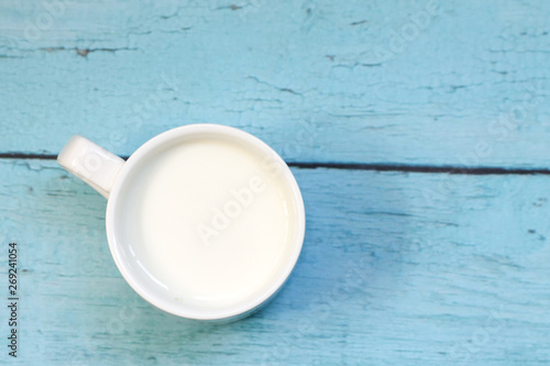 White cup with milk on a blue wooden table. Background.