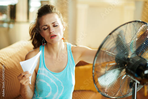 hot woman in front of working fan suffering from summer heat