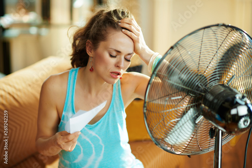 Fototapeta housewife in front of fan suffering from summer heat