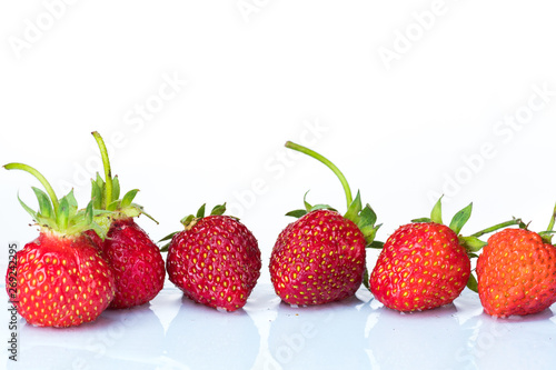 Several ripe wet red strawberries on white or colored background with splashes of water