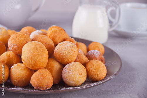 Small balls of freshly baked homemade cottage cheese doughnuts in a plate on a gray background.
