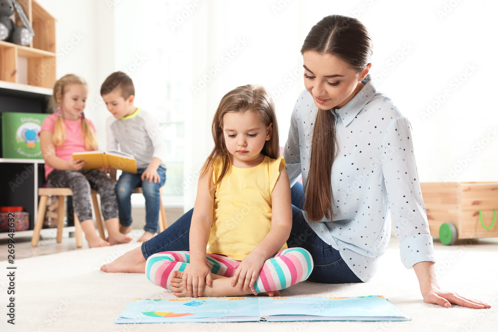 Kindergarten teacher reading book to child indoors. Learning and playing Kindergarten teacher reading book to child indoors. Learning and playing