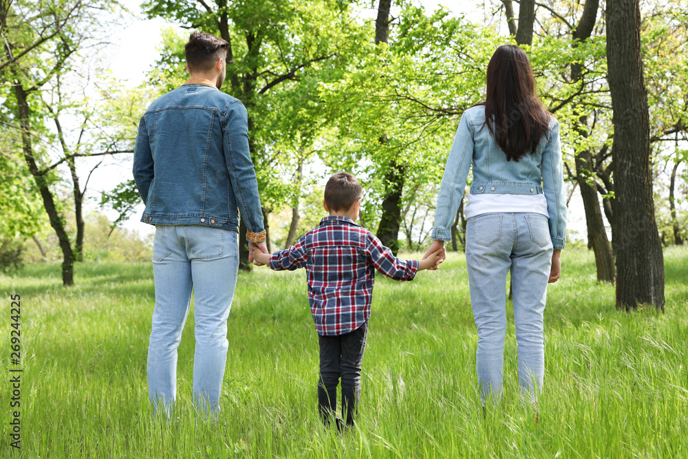 Little child holding hands with his parents in park. Family time Little child holding hands with his parents in park. Family time