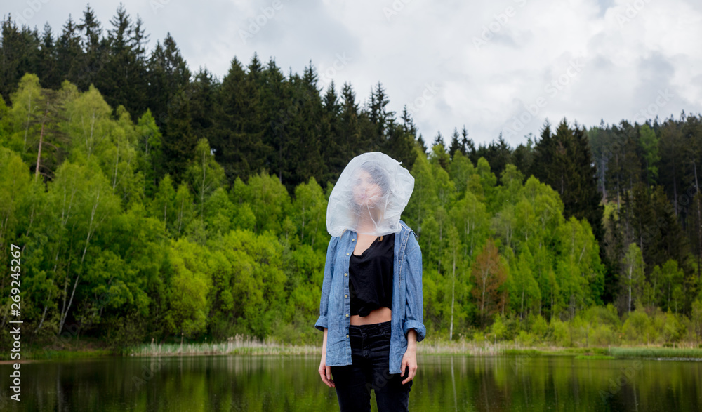 girl with cellophane bag on her head near the lake and the forest girl with cellophane bag on her head near the lake and the forest