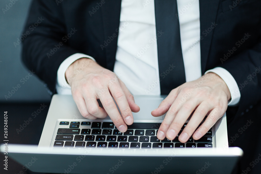 Hands of businessman typing on laptop computer placed on his lap, close-up top view Hands of businessman typing on laptop computer placed on his lap, close-up top view