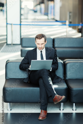 Foto Intelligent businessman sitting on leather couch in airport lounge or office lob