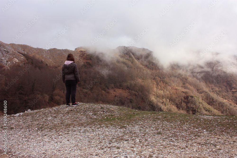 girl walks alone in the mist and fog along the paths of the Apuan Alps in Tuscany