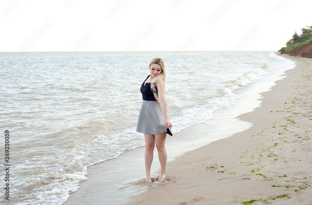 girl walking on the beach in cloudy weather, in a dress