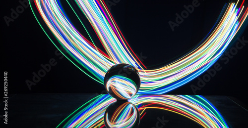 Light painting with crystal ball using led Christmas colorful lights and light reflection on glass with selective focus