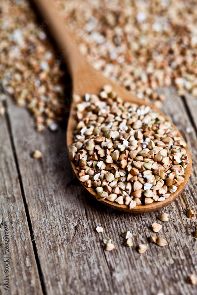 Organic green dry buckwheat seads in wooden spoon closeup on rustic background. Organic green dry buckwheat seads in wooden spoon closeup on rustic background.