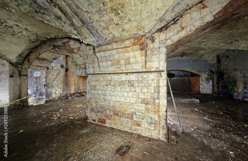 A wide column of an abandoned building lined with white tiles covered with dirt, cracks and smudges.