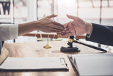 Handshake after good cooperation, Businesswoman Shaking hands with Professional male lawyer after discussing good deal of contract in courtroom, Concepts of law, Judge gavel with scales of justice