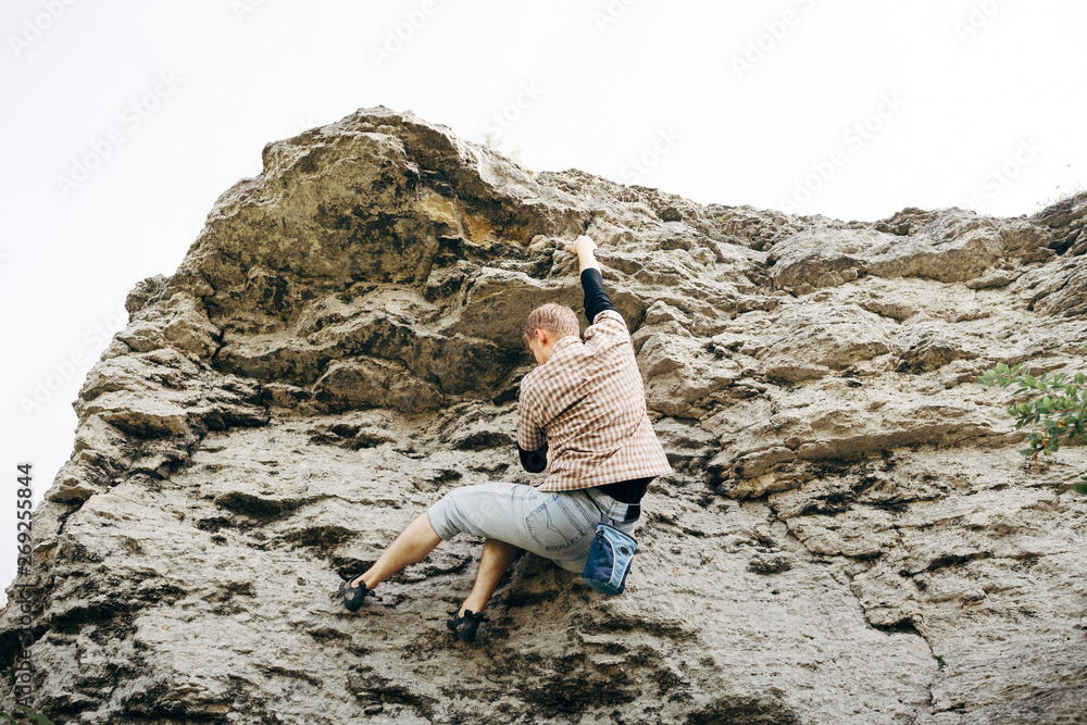 Brave young man climbs the cliff