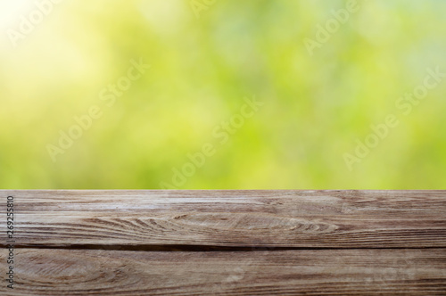 Wood table top on shiny bokeh green background. For product display.