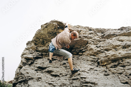 Brave young man climbs the cliff