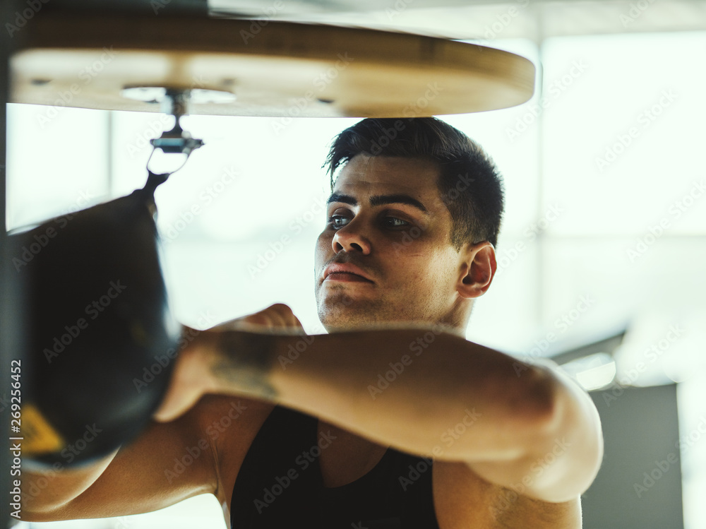 Side view of young boxer practicing hand speed drill using small punching  bag in boxing gym.. Stock Photo | Adobe Stock