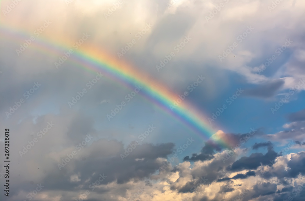 Rainbow in the spring cloudy sky after a thunderstorm.