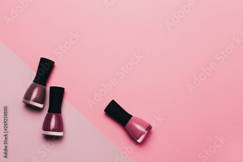 Closeup view of nail polish in trendy berry, purple and lilac colors with sparkles on color background. Flat lay, copy space. Taking care of yourself and hands, beauty salon, summer mood.