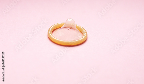 Close up of a condom on pink background. Minimal trendy style.