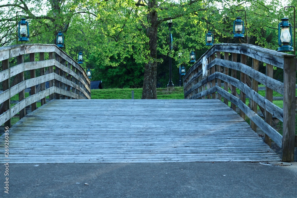 wooden walkway bridge with railing lined with blue lanterns for light