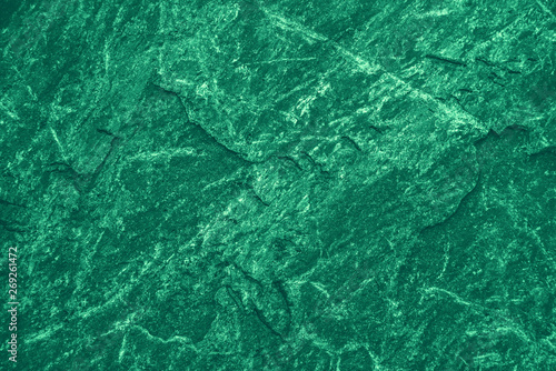 Vintage green background. Rough painted wall of emerald color. Imperfect plane of virid colored. Uneven old decorative toned backdrop of green tint. Texture of emerald hue. Ornamental stony surface. © Daniil