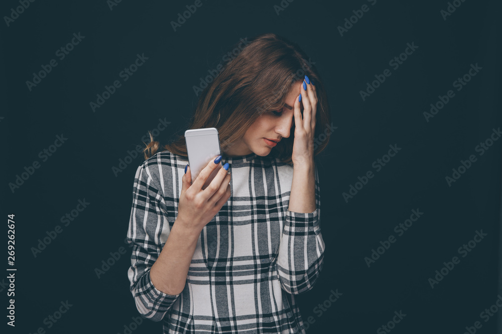 Sad teen being victim of cyber bullying online sitting on a couch in the living room at home Sad teen being victim of cyber bullying online sitting on a couch in the living room at home